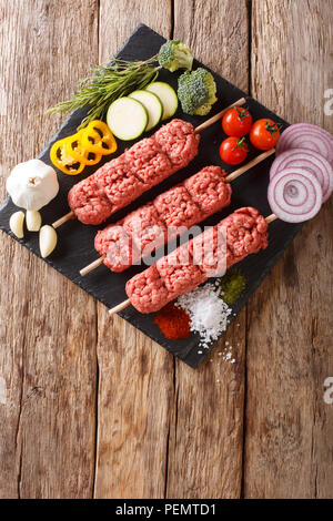 Raw kebab Rinderhackfleisch mit Zutaten und Gemüse close-up auf den Tisch. Vertikal oben Ansicht von oben Stockfoto