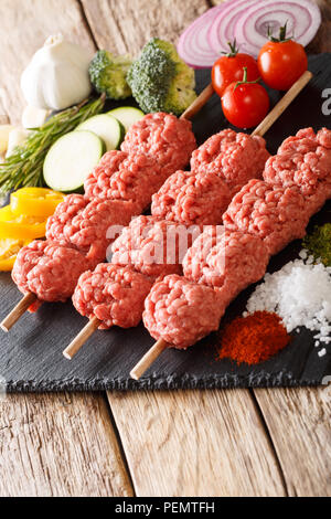 Türkische Rohstoff Kebab aus Hackfleisch/Faschiertem auf Spieße mit Zutaten und Gemüse close-up auf dem Tisch. Vertikale Stockfoto