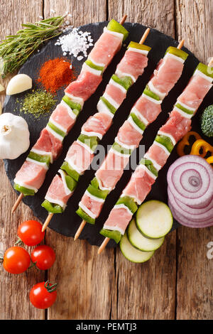 Raw Shish Kebab mit grünem Pfeffer auf Spieße close-up und Gemüse, Kräuter auf dem Tisch. Vertikal oben Ansicht von oben Stockfoto