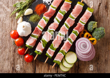 Raw Shish Kebab mit grünem Pfeffer auf Spieße close-up und Gemüse, Kräuter auf dem Tisch. Horizontal oben Ansicht von oben Stockfoto