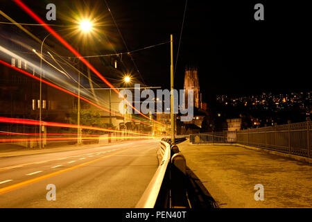 Lange Belichtung Night Shot von Fribourg in der Schweiz, mit Fahrzeug leichte Wanderwege auf der linken und die Saint-Nicolas Kathedrale auf dem Hintergrund Stockfoto