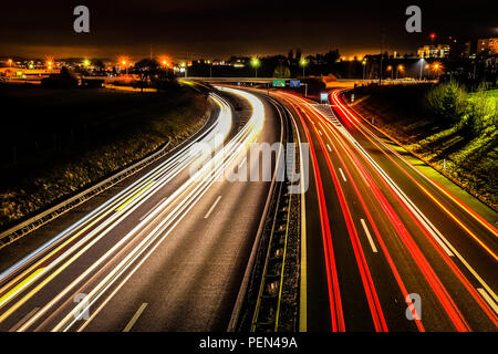 Lange Belichtung Night Shot einer Autobahn in der Region Freiburg in der Schweiz, mit hellen und farbenfrohen Fahrzeug leichte Wanderwege und der öffentlichen Beleuchtung Stockfoto