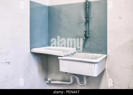 Alte vintage Waschbecken mit Kupfer Wasserhahn mit einem grauen Hintergrund. Stockfoto