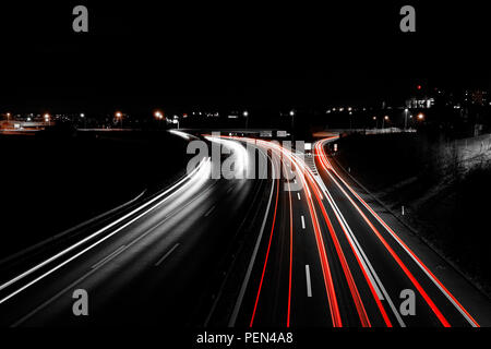 Lange Belichtung Night Shot einer Autobahn in der Region Freiburg in der Schweiz, mit den leichten Wanderwegen und öffentlichen Lichter im Hintergrund Stockfoto