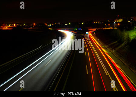 Lange Belichtung Night Shot einer Autobahn in der Region Freiburg in der Schweiz, mit Fahrzeug leichte Wanderwege und der öffentlichen Beleuchtung Stockfoto