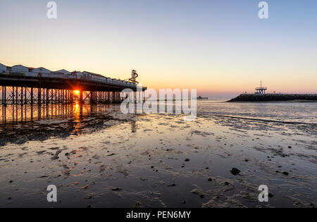 Sonnenuntergang pokes durch Lücken in Herne Bay Pier an der Küste von Kent. Anzeigen von Herne Bay pier, Arm Neptuns und der alte Pier. Stockfoto