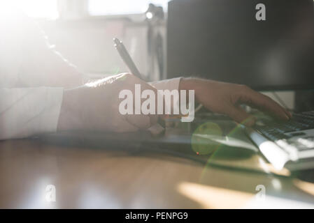 Fotograf Skizzieren und Zeichnen mit einem Stift auf Grafik Tablett in einem Strahl von helles Licht bei Sun flare von einem Fenster in der Nähe zu sehen. Stockfoto