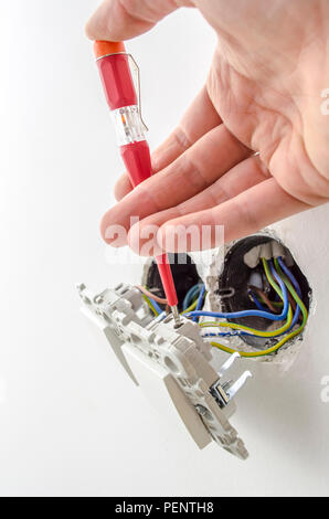 Nahaufnahme von einem Elektriker Prüfung von elektrischen Spannung an einen Lichtschalter. Stockfoto