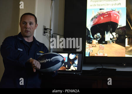 Lt. Joel Wright, Coast Guard Cutter's Polar Star Operations Officer, verwendet einen rugby ball, um zu erklären, wie einzigartige Form des Werkzeugs Rumpf bricht Eis während einer Trainingseinheit Jan. 1, 2016. Polar Star, des Stärksten nicht-nuklearen Eisbrecher, wurde speziell für den Einsatz in einige der unwirtlichsten Orte auf der ganzen Welt zu bedienen. (U.S. Coast Guard Foto von Petty Officer 2. Klasse gewähren DeVuyst) Stockfoto