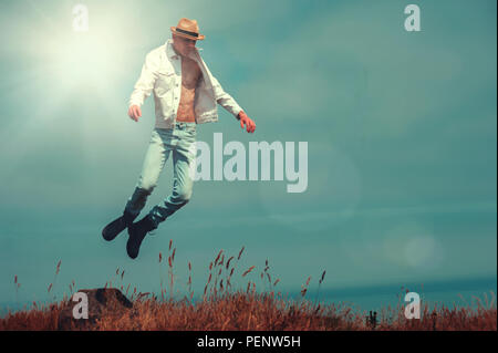 Junger Mann fliegen in den Feldern auf dem Cliff Stockfoto