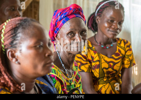 Eine ältere Frau, Lächeln für die Kamera von ihrem Sitz in einem Gottesdienst in Ganta, Liberia Stockfoto