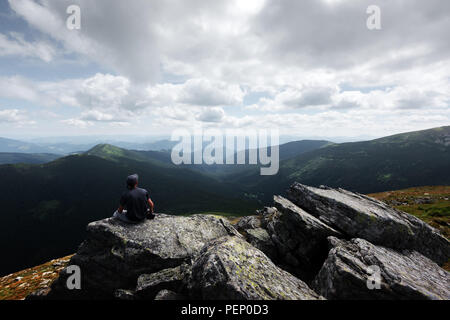 Eine einsame Touristen sitzen auf dem Rand der Klippe Stockfoto