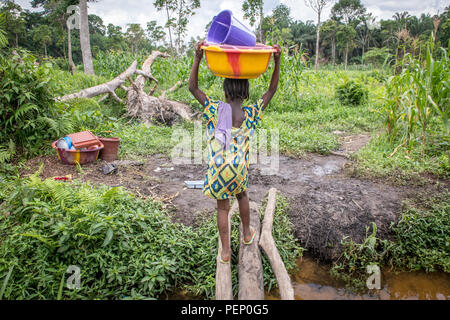 Ein junges Mädchen trägt eine bunte Eimer auf dem Kopf in Ganta Liberia Stockfoto