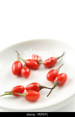 Frische Goji Beeren in einer kleinen weißen Schale auf einen weißen Hintergrund mit Kopie Raum isoliert Stockfoto