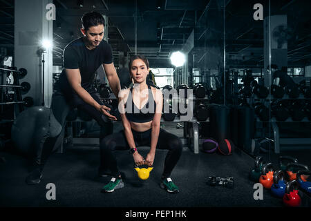 Passen junge Frau in Sportkleidung auf dem Anheben einer Hantel während einer Übung Klasse in einem Fitnessstudio konzentriert Stockfoto