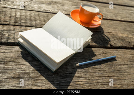 Leeres weißes Buch mit Bleistift und Kaffee Tasse über alten verwitterten Holztisch zum Thema über Erinnerungen und Selbstbeobachtung. Stockfoto