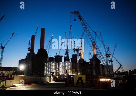 Krane und Bauarbeiten leuchtet in der Dämmerung an der Battersea Power Station, London - 16. August 2018. Das denkmalgeschützte Gebäude und Umgebung wird Sie in eine luxuriöse Unterkunft und Freizeit Entwicklung gedreht. Stockfoto