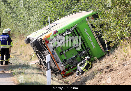 Linstow, Deutschland. 17 Aug, 2018. Feuerwehrleute stehen an einem Flixbus, die in den Graben der Autobahn A19 Rostock-Berlin. Nach Angaben der Polizei wurde der Flixbus ging von der Straße auf der rechten Seite und fiel in den Graben aus unbekannten Gründen. Es kippte auf die Seite. Zahlreiche Menschen wurden verletzt. Quelle: Bernd Wüstneck/dpa-Zentralbild/dpa/Alamy leben Nachrichten Stockfoto