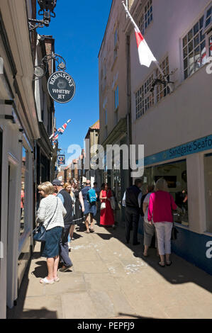 Touristen Besucher, die im Sommer Sandgate Whitby North Yorkshire England Großbritannien und Großbritannien durch das Stadtzentrum spazieren Stockfoto