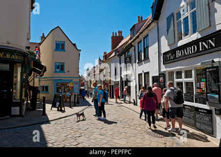 Die Menschen Touristen Besucher Geschäfte und Pubs in der Innenstadt im Sommer Church Street Whitby North Yorkshire England Großbritannien GB Großbritannien Stockfoto