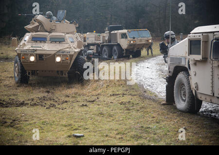 Us-Soldaten zu 554Th Military Police Company wieder Feuer an der Szene eines aufgeschlüsselt Humvee, nachdem sie unter Feuer von den Kräften der Opposition während der Wiederherstellung des Fahrzeugs Ausbildung kommen, Teil eines Feldes Training übung in Boeblingen lokale Schulungen, Jan. 13, 2016. (U.S. Armee Foto von visuellen Informationen Spezialist Martin Greeson/Freigegeben) Stockfoto