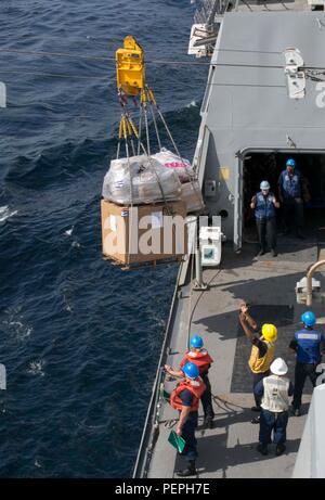 Ein Seemann der US Navy an Bord der USS Arlington (LPD 24) signalisiert die USNS Medgar Evers (T-AKE 13) während des Frachttransfers im Golf von Oman am 8. Januar 2016. Diese Operation zur Wiederauffüllung auf See unterstützt die Kearsarge Amphibious Ready Group und die 26th Marine Expeditionary Unit, um die regionale Sicherheit im Gebiet der 5. US-Flotte zu gewährleisten, die Einsatzbereitschaft aufrechtzuerhalten und die Fähigkeit zur maritimen Logistik und zur Koordination von Schiff zu Schiff während des laufenden Betriebs unter Beweis zu stellen. Stockfoto
