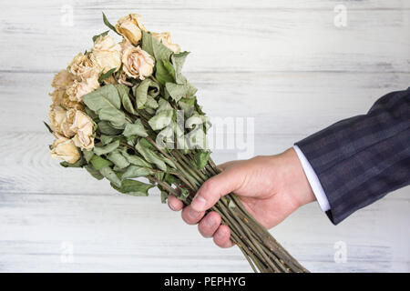 Getrocknete Blumenstrauß aus den weißen Rosen in der Hand des Kaufmanns. Stockfoto