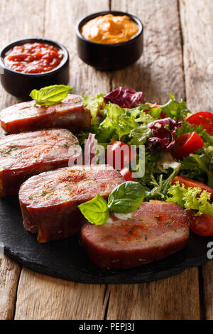 Pikanter Schweinebraten Brustbein und frischem Salat serviert Ketchup und Senf auf dem Tisch. Vertikale Stockfoto