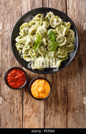 Gekochten Spinat grün Cappelletti, Ravioli, Tortellini, gefüllt mit Fleisch mit Parmesan und Basilikum mit Saucen in der Nähe serviert - auf den Tisch. Verti Stockfoto