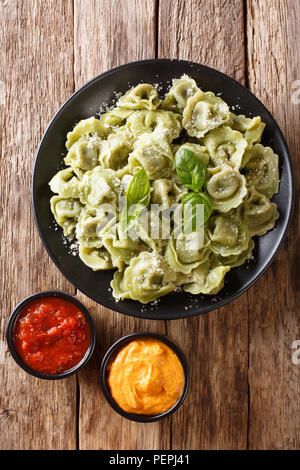 Italienische Küche authentische Rezept Spinat grün Cappelletti, Ravioli, Tortellini mit Fleisch und Parmesan Käse, Basilikum mit Soßen serviert in der Nähe auf. Stockfoto