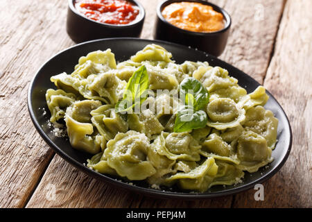 Italienische Küche authentische Rezept Spinat grün Cappelletti, Ravioli, Tortellini mit Fleisch und Parmesan Käse, Basilikum mit Soßen serviert in der Nähe auf. Stockfoto