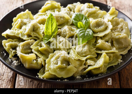 Italienische grüne Spinat Cappelletti, Ravioli, Tortellini, gefüllt mit Fleisch und Parmesan und Basilikum close-up auf einem Teller auf dem Tisch. Horizontale Stockfoto