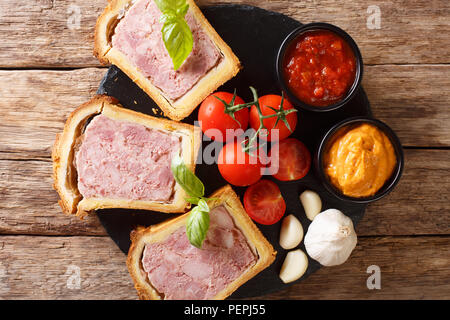 Fleisch Terrine, Pastete mit Gewürzen, Knoblauch mit Gemüse und Saucen in der Nähe serviert - auf den Tisch. Horizontal oben Ansicht von oben Stockfoto