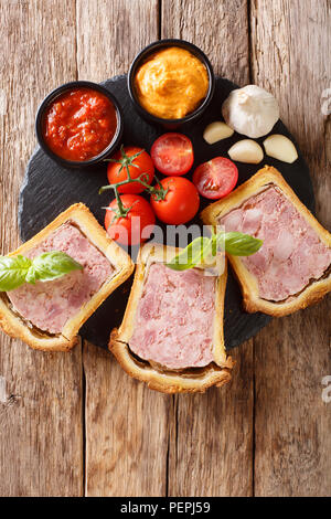 Fleisch Terrine, Pastete mit Gewürzen, Knoblauch mit Gemüse und Saucen in der Nähe serviert - auf den Tisch. Vertikal oben Ansicht von oben Stockfoto