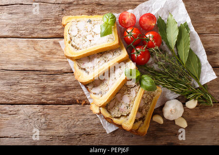 Brioche mit einer Füllung aus Huhn Terrine mit Gewürzen, Knoblauch und Kräuter close-up auf Papier auf einem Tisch. horizontal oben Ansicht von oben Stockfoto