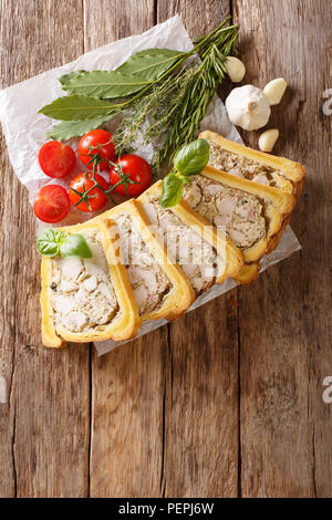 Brioche mit einer Füllung aus Huhn Terrine mit Gewürzen, Knoblauch und Kräuter close-up auf Papier auf einem Tisch. Vertikal oben Ansicht von oben Stockfoto