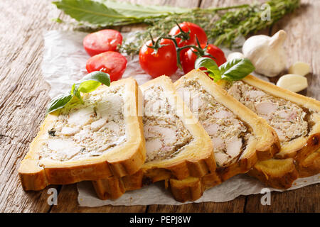 Fleisch Huhn Terrine, Jelly in Brot mit Gewürzen und Kräutern close-up auf Papier auf Tisch. Horizontale Stockfoto