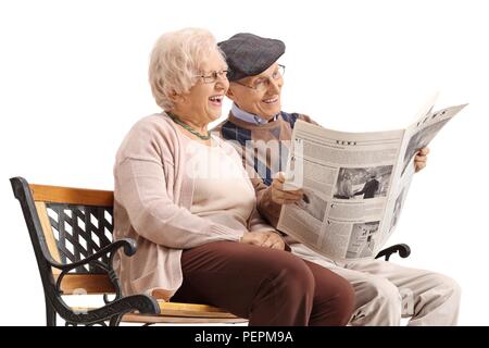 Senior Paar sitzt auf einer Bank eine Zeitung lesen und auf weißem Hintergrund lachen isoliert Stockfoto