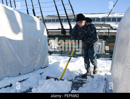Ein Schiffssoldat der 2. Klasse räumt am 24. Januar 2016, nach dem ersten Wintersturm im Jahr 2016, Schnee an Bord der USS Constitution in Charlestown Navy Yard. Das Schiff befindet sich im Dry Dock 1 für Rumpf- und Rahmenreparaturen. Zu den Tätigkeiten gehören Instandhaltung, strukturelle Inspektion, Erhaltung, Hafenunterstützung, historische Schiffsinstandhaltung, und Vorbereitung auf die Marinefreiheit. Stockfoto