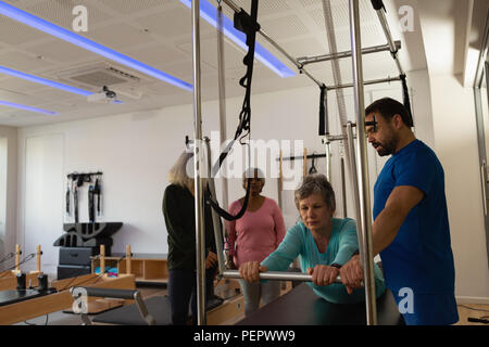 Trainer Unterstützung älterer Frauen bei der Durchführung von Yoga Stockfoto