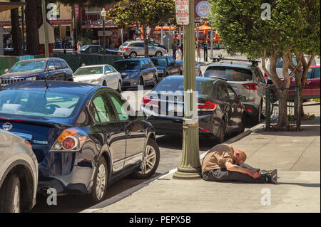 Obdachloser Mann schlief auf dem Bürgersteig durch den Mast in San Francisco, Kalifornien, USA. Stockfoto