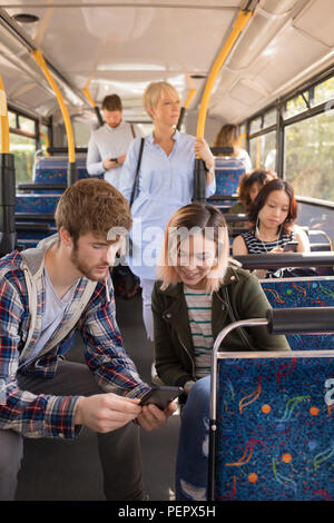Paar mit Handy während der Fahrt in modernem Bus Stockfoto