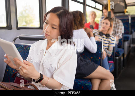 Weibliche Pendler mit digitalen Tablet bei Reisen im modernen Bus Stockfoto