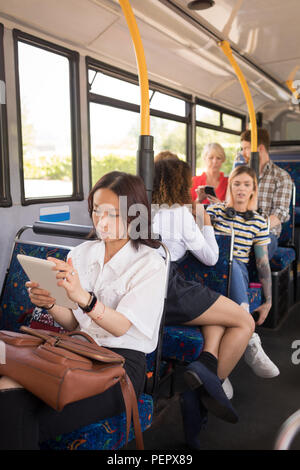 Weibliche Pendler mit digitalen Tablet bei Reisen im modernen Bus Stockfoto