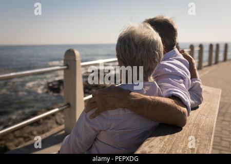 Senior Paar auf der Bank mit den Armen herum Stockfoto