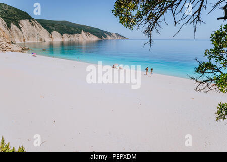 Erstaunlich Fteri Beach Lagoon, Kefalonia, Griechenland. Touristen unter dem Dach Chill in der Nähe von blauen Smaragd türkis Meer Wasser entspannen. Cliff rock Küste im Hintergrund Stockfoto