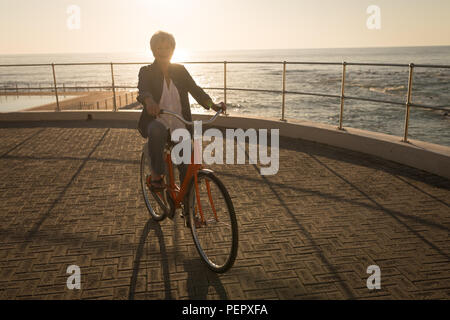 Ältere Frau Reiten Fahrrad an der Promenade Stockfoto
