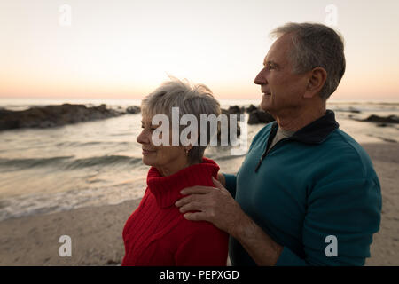 Senior Paar stehen am Strand bei Sonnenuntergang Stockfoto