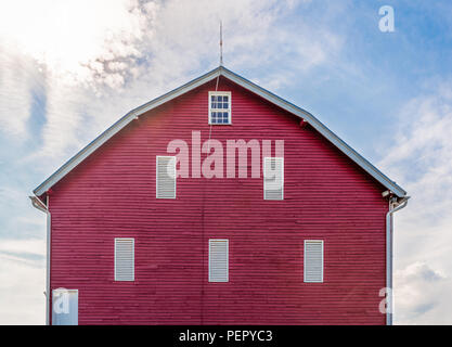 Eine helle rote Scheune auf Ackerland in West Virginia unter der hellen Sonne in einem leicht bewölkt blauen Sommerhimmel Stockfoto