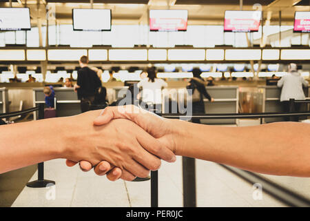 Menschen die Hände schütteln im Flughafen Terminal mit unscharfen Leute im Hintergrund. Stockfoto